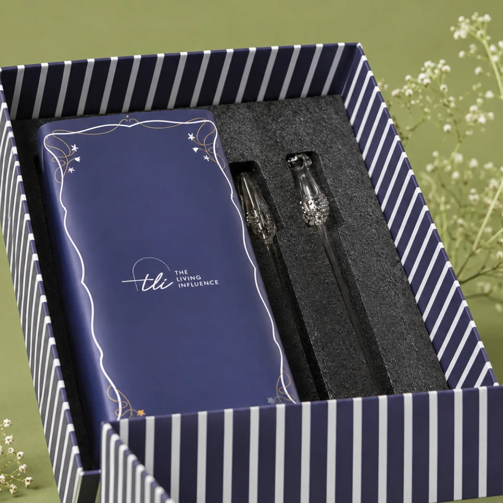A gift set presented in a navy and white striped box, containing a dark blue box of vase and two clear glass stems.