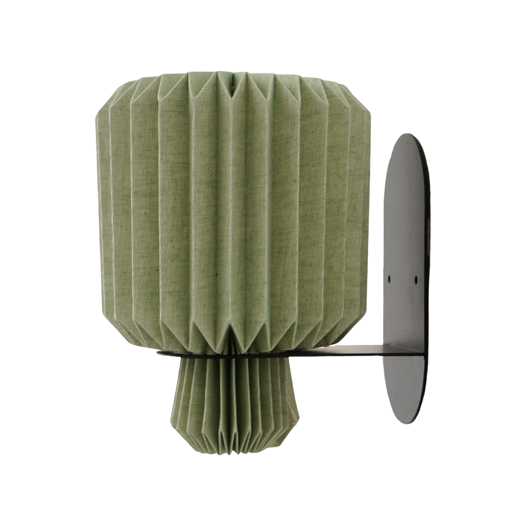 A wall-mounted lamp with a green, origami-inspired linen shade and a metallic bracket.