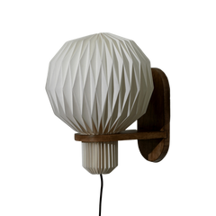 A white pleated sconce wall lamp with a geometric design, mounted on a braided textile cable.