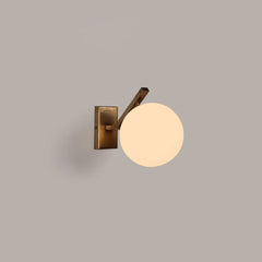 Molt Wall-mounted lamp with a round glass shade, casting warm light