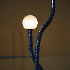 Closer look of Reva Floor lamp with a spherical bulb against a dark background