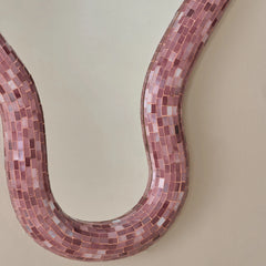 Close view of Mosaic mirror with pink tiles on a beige wall