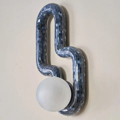 Decorative wall sconce with blue mosaic design on a beige wall