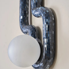 Close up of decorative wall sconce with blue mosaic design and paired with a frosted glass sphere