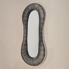 Decorative wall mirror with black wireframe design on a beige wall
