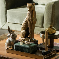 Decorative items including a green storage box, standing cat figurine, rabbit figurine, and cactus on a wooden surface.