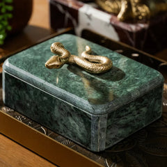 Green marble jewelry box with a gold snake decoration on a wooden surface.