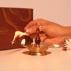Baby Vilakku Oil Lamp wicks being lit with a matchstick, brass saucer with amber glass finial