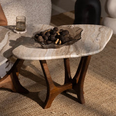 Small marble table with wooden legs holding a decorative bowl on a carpeted floor.