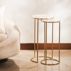 Two gold side tables with white tops in a living room setting.