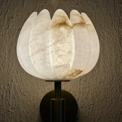 A modern Lotus Alabaster Wall Sconce featuring a textured, translucent white stone shade with warm golden-brown veining