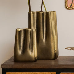 Decorative two gold metallic peru vases on a wooden surface with a neutral background