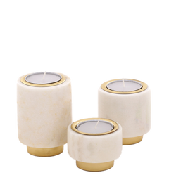 A set of three pillar-shaped marble tealight holders with brass bases and rims, in different sizes, displayed against a neutral background.