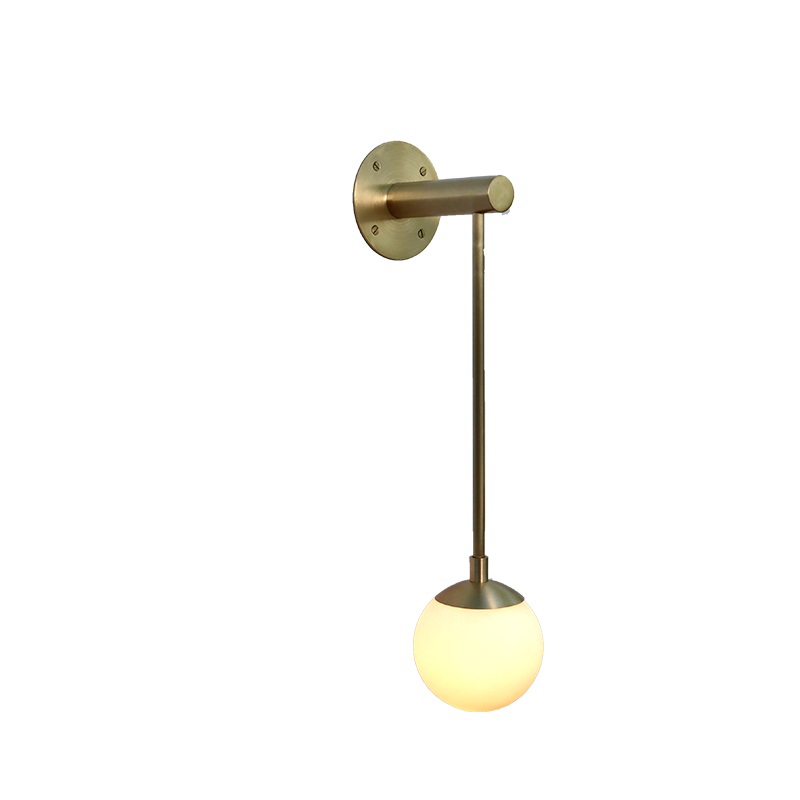 A Dot series wall-mounted sconce with a long glass globe and a brass base and stem.