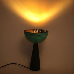 Table lamp with a greenish bowl-shaped shade and black base on a plain background