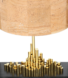 Close view of city of light table lamp with a brass cityscape base and a cork sheet shade.