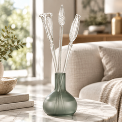 A frosted sage green glass vase with three long clear glass sticks topped with flower tulip-like flared ends.