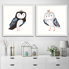 Two framed art pieces depicting stylized owls with crowns, displayed on a wall above a cabinet with decorative items.