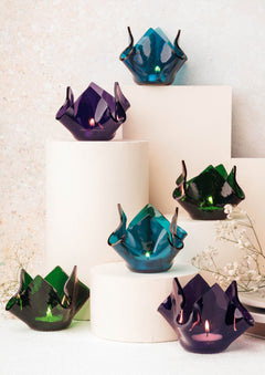 Set of colorful glass crumpled candle votives on a white surface with a neutral background