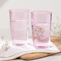 Two pink borosilicate glass lowball glasses with a flower pattern, placed on a white cloth.