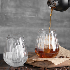 Premium two stemless glasses with a straight ribbed design, placed on a white surface, with drink poured in one glass