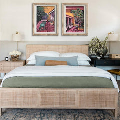 A set of two framed art prints depicting vibrant cityscapes, displayed above a bed in a room with modern decor.