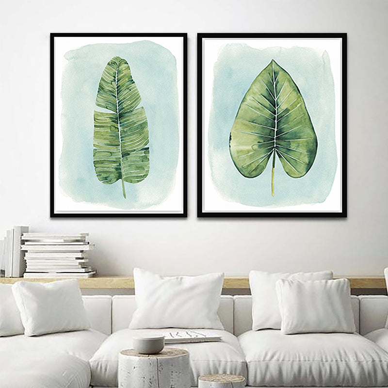 Two framed leaf prints hanging on a wall , depicting watercolor illustrations of green leaves on a light background.
