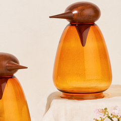 Chirp Penguin - Two glass bird-shaped serveware, orange glass body with wooden brown top, on a light background.