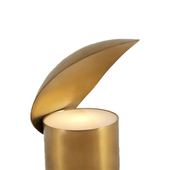 Unique gold colored table lamp with a shell-like design on a cylindrical base
