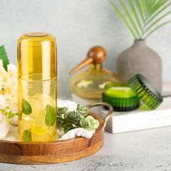Clear Juliette Glass Carafe in yellow color on a wooden tray with greenery, against a neutral background.