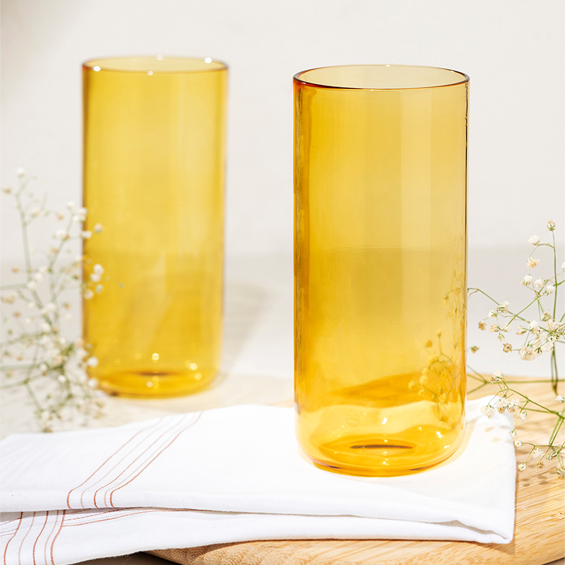 Juliette Cocktail Glasses in yellow, borosilicate glasses placed on a wooden board with a white napkin beside them.